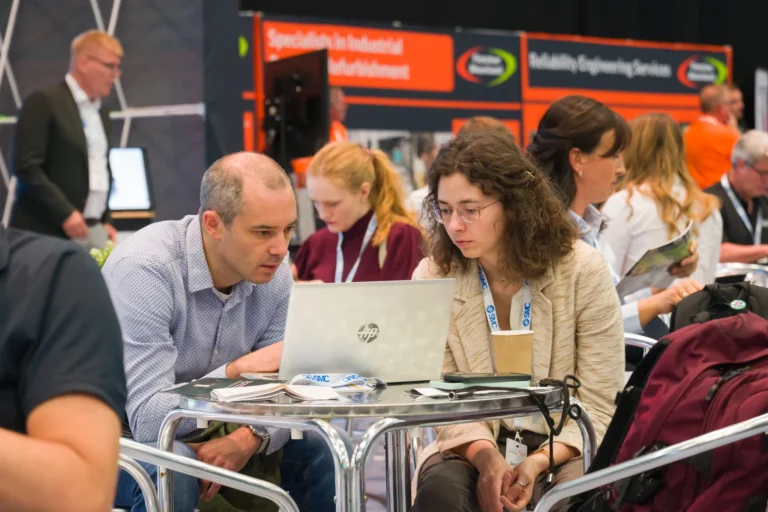Delegates discussing information on a laptop at the 2026 Sustainable Food Factory and Food+Beverage Engineering event.